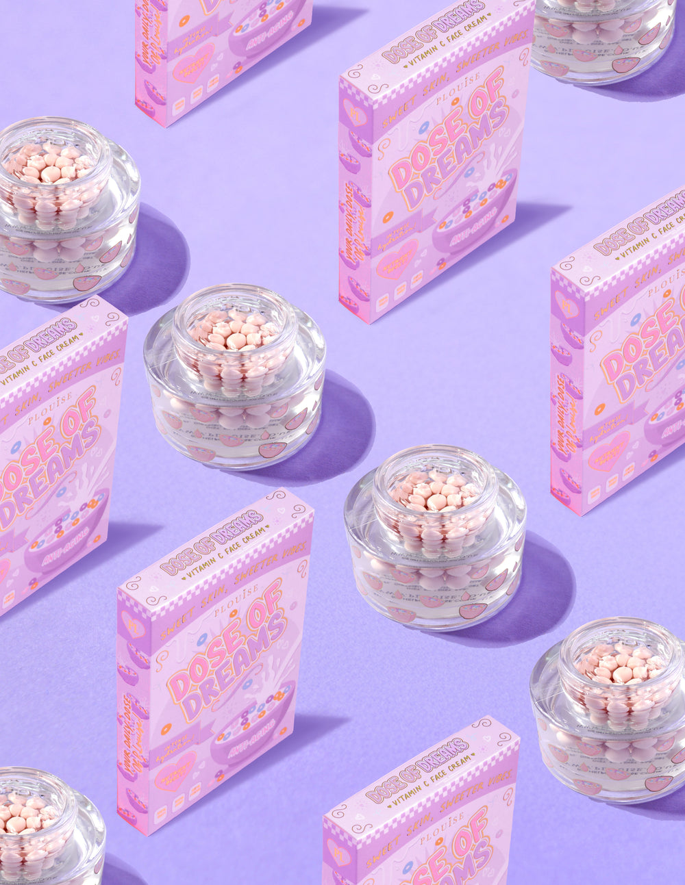 Klare beholdere med P.Louise DOse of Dreams Vitamin C Capsule Face Cream med pink kapsel i omgivet af lyserøde kornkasser på en lilla baggrund