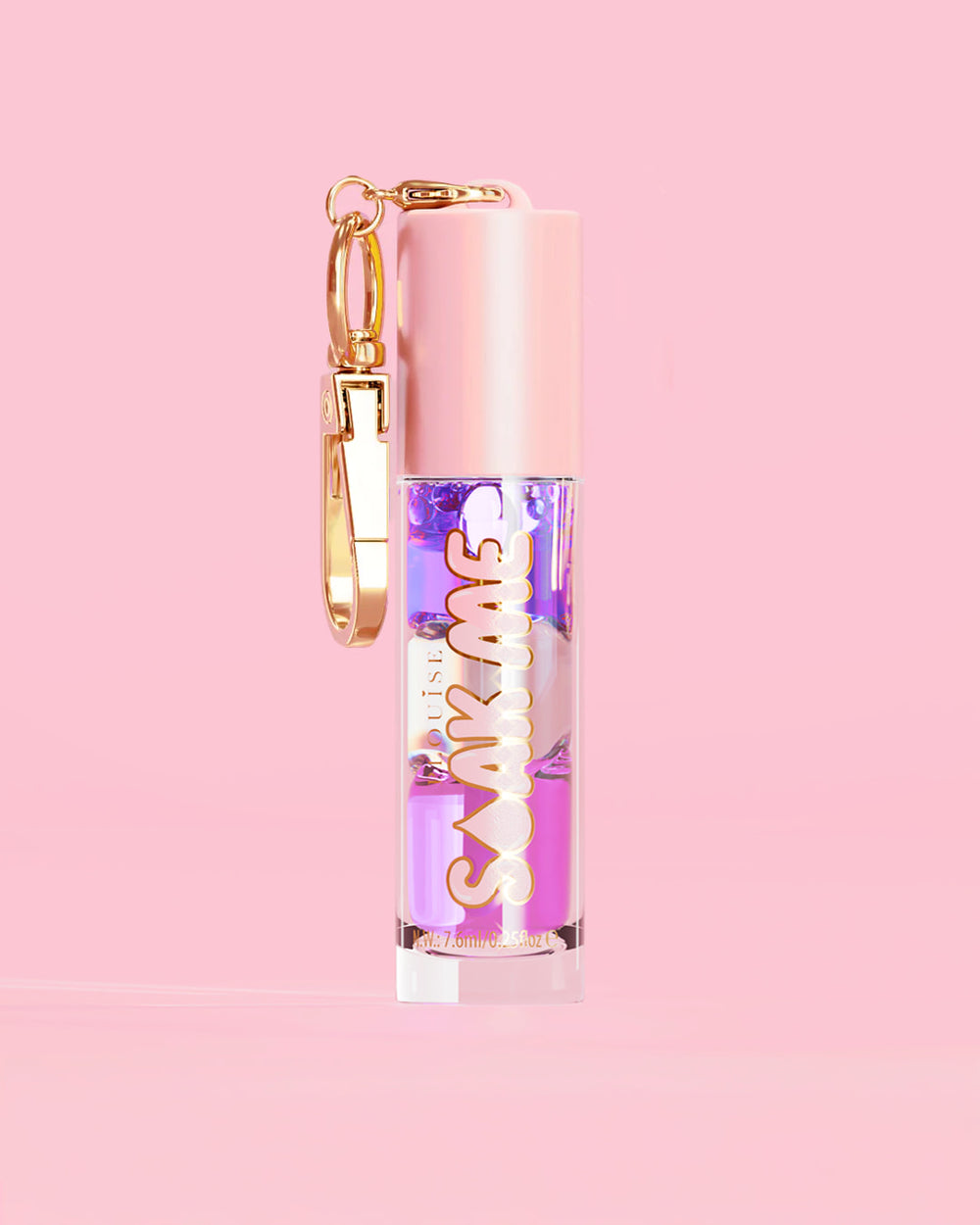 P. Louise Soak Me Lip Oil con aceite en capas de colores en un tubo rosa con un cierre dorado sobre un fondo rosa