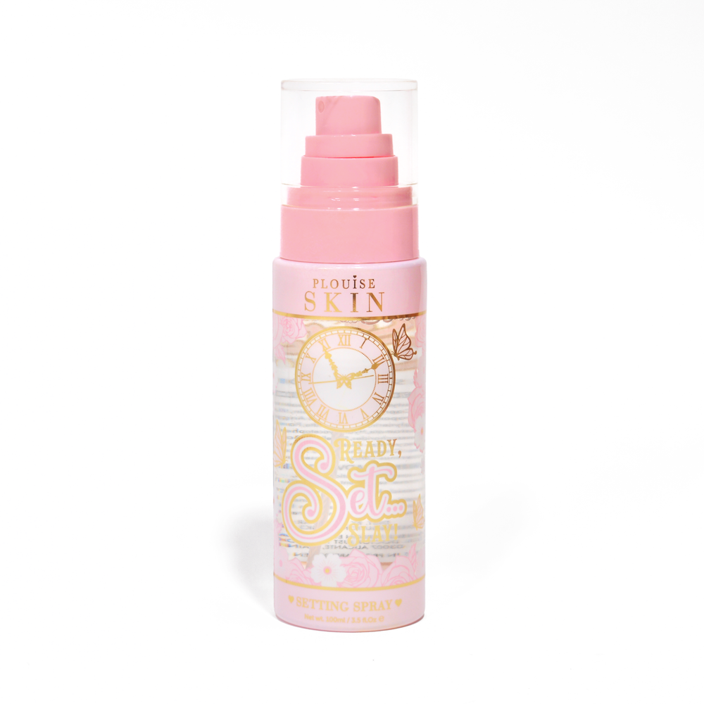 Una botella rosa de P. Louise Ready Set Slay Spray fijador de larga duración sobre un fondo blanco.