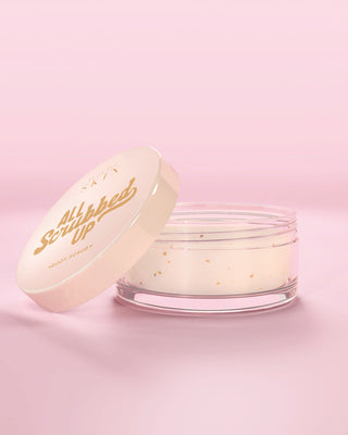 Jar of P.Louise All Scrubbed Up body scrub in coconut cake scent with a pink background