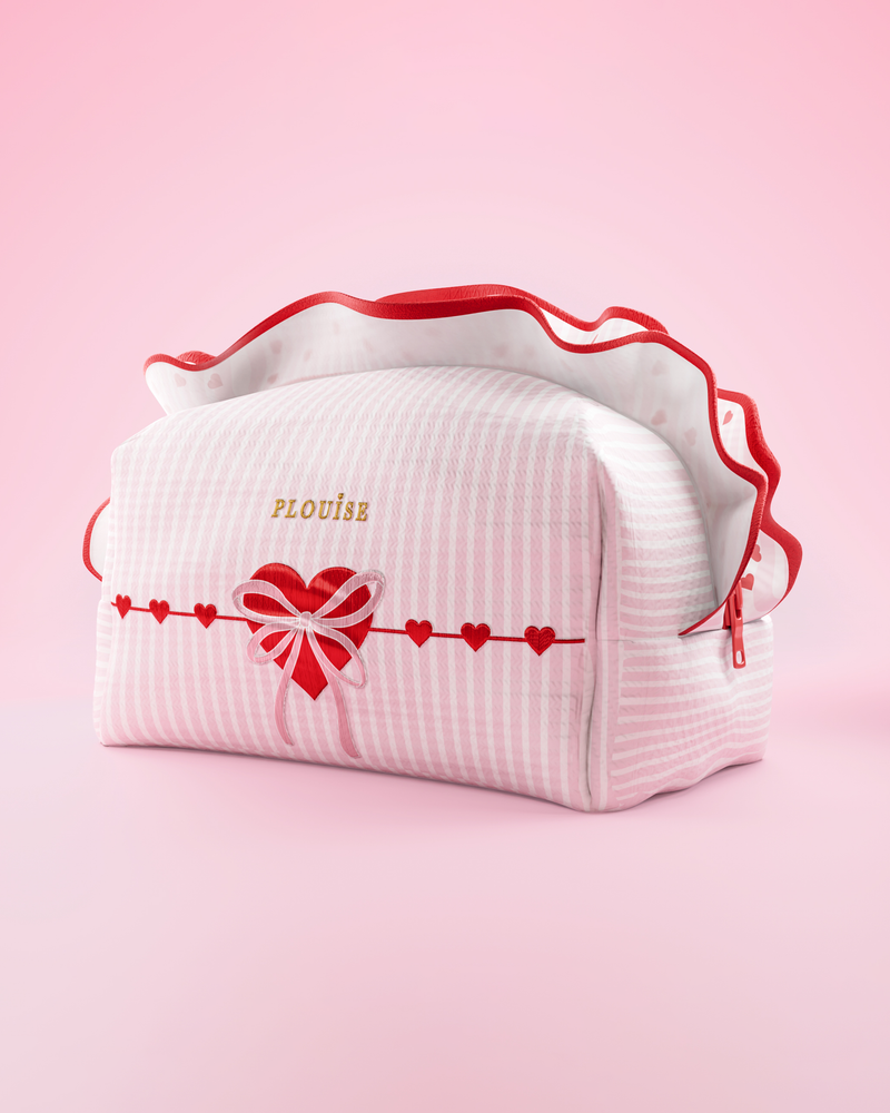 Un bolso de maquillaje y cuidado de la piel P.Louise a rayas rosas y blancas con volantes y un diseño de corazón sobre un fondo rosa