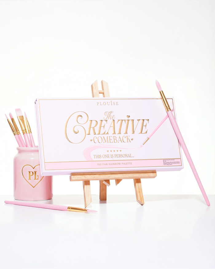 En lukket pink P.Louise Creative Comeback XXXL Rainbow Eyeshadow Palette placeret på et staffeli omgivet af makeup-børster
