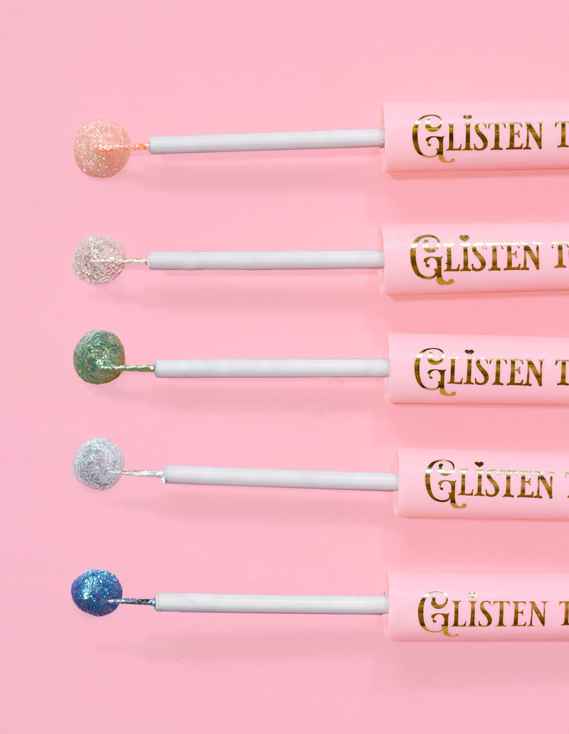 5 P.Louise Glisten To Your Heart glitter eyeliners linet op med et dryp af produktet på enden mod en lyserød baggrund