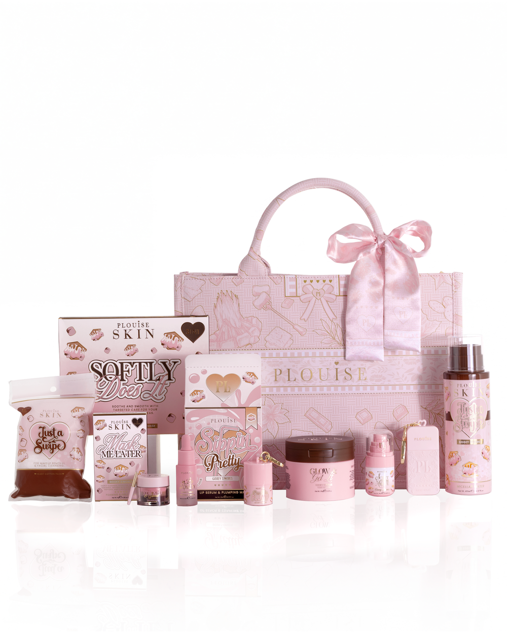 Una colección de cestas boo rosa de la marca Plouise, que presenta un bolso tote grande estampado con un lazo de satén y varios otros productos rosados para el cuidado de la piel y fragancias dispuestos sobre una superficie blanca reflectante.
