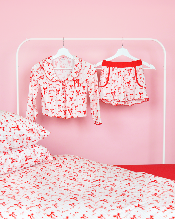 Sæt med pink og hvidstribede piger P.Louise julesløjfe pyjamasshorts på bøjler i et pink soveværelse med matchende sengetøj 