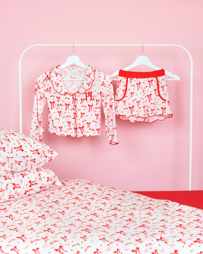 Sæt med pink og hvidstribede piger P.Louise julesløjfe pyjamasshorts på bøjler i et pink soveværelse med matchende sengetøj 