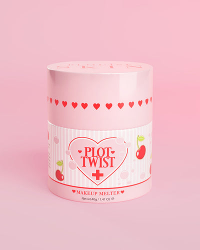 En lyserød beholder med P.Louise Plot Twist Makeup Melting Cleansing Balm med hjerte- og kirsebærdesign på etiketten mod en lyserød baggrund