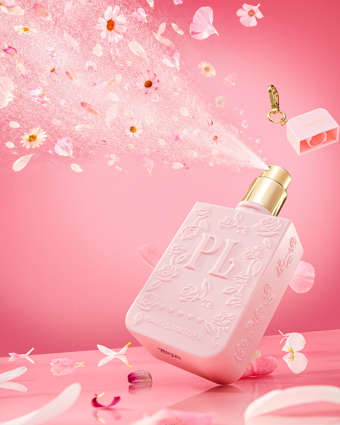 Pink bottle of P.Louise Hand Sanitiser Spray in signature scent with gold cap on a pink background with floral elements