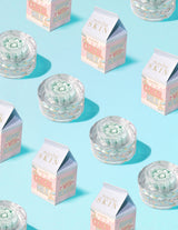 Klare beholdere med P.Louise Dose of Dreams Vitamin C Kapselcreme med blå kapsel indeni omgivet af mælkekartoner
