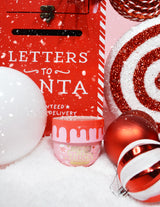 Un frasco de P.Louise Lay It On Thick Body Butter en la variante Frosted Peppermint, exhibido con decoraciones navideñas a su alrededor, incluidas luces navideñas y regalos.
