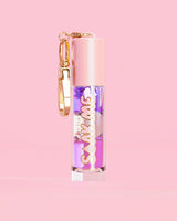 P. Louise Soak Me Lip Oil con aceite en capas de colores en un tubo rosa con un cierre dorado sobre un fondo rosa