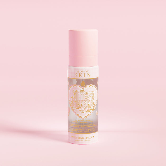 En lyserød sprayflaske mærket 'P.Louise SKIN' med en afbildning af et hjerte og nogle blomsterelementer, indeholdende en fugtgivende setting spray.