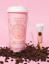 Una imagen de producto que muestra un lápiz de cejas de doble punta junto a un tubo de gel para cejas, mostrado sobre una superficie rosa con granos de café esparcidos por todas partes. El fondo tiene una taza de café rosa con elementos de marca.