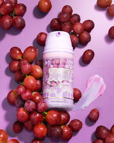 Lilla flaske P. Louise Here I Glow Again Grape Recovery Mask omgivet af druer på en lilla baggrund