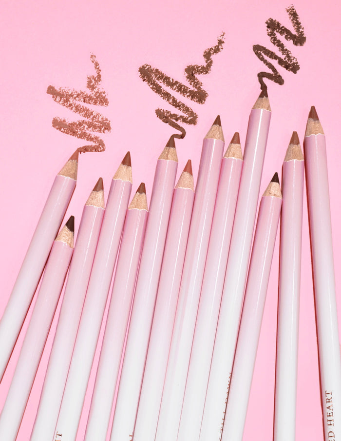 Et billede af flere P.Louise Ultimate Definition Sharpenable Lip Liners grupperet sammen, der viser noget produkt tegnet over dem på en lyserød baggrund