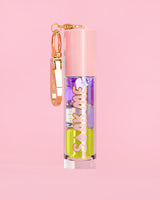 P. Louise Soak Me Lip Oil con aceite en capas de colores en un tubo rosa con un cierre dorado sobre un fondo rosa